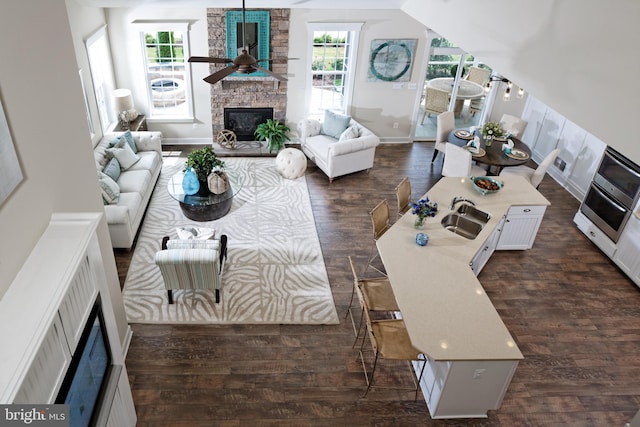 living room featuring ceiling fan, dark hardwood / wood-style floors, sink, and a fireplace