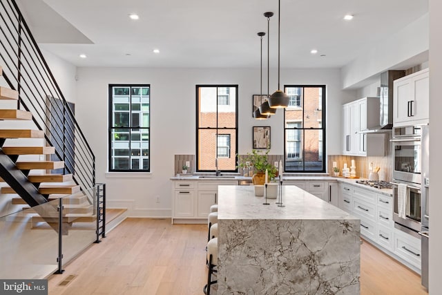 kitchen featuring stainless steel appliances, a center island, light wood-type flooring, and white cabinets