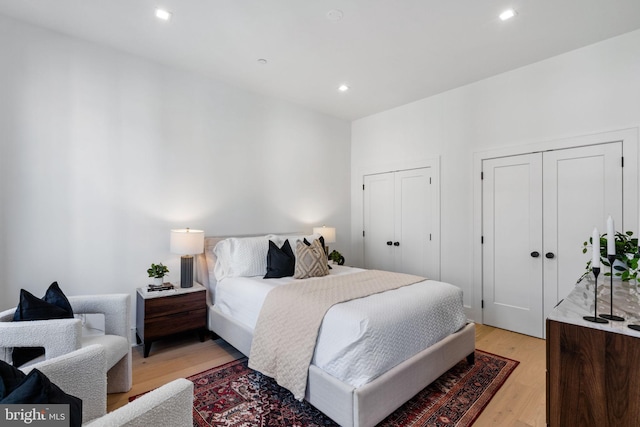 bedroom with multiple closets and light hardwood / wood-style floors