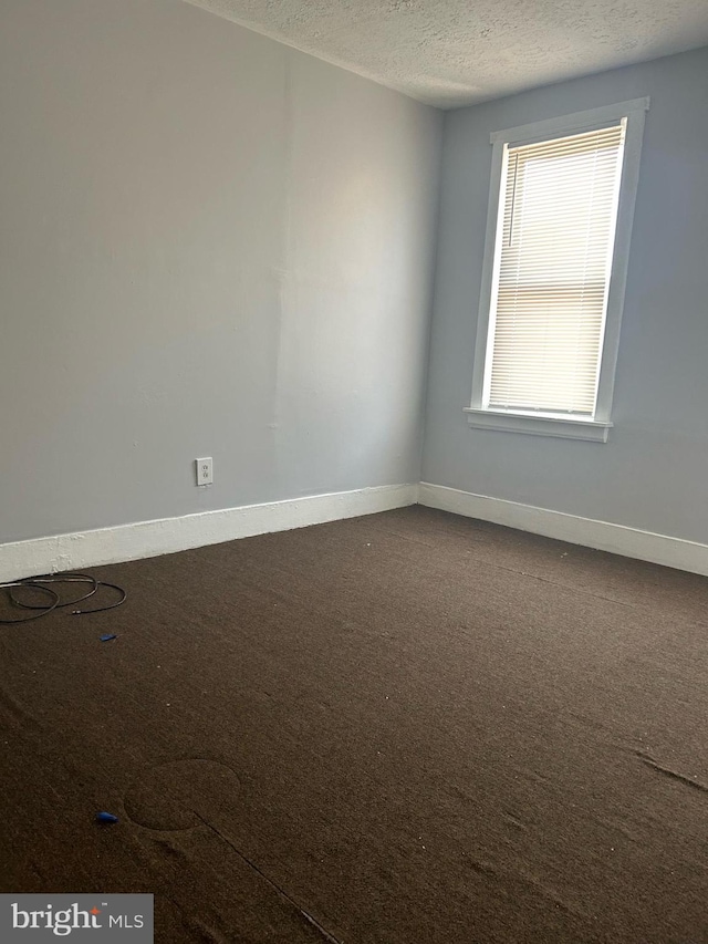 unfurnished room featuring a textured ceiling and carpet