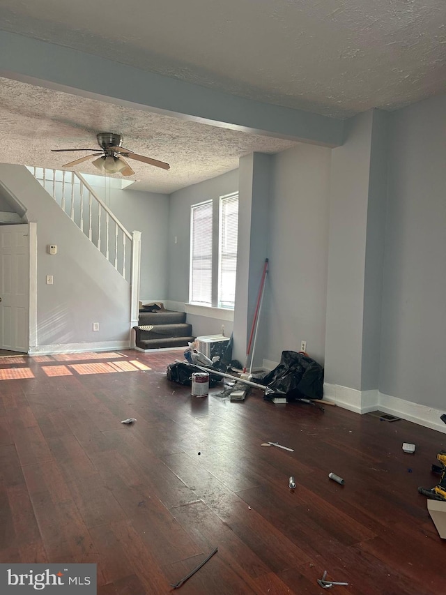 unfurnished living room with ceiling fan, wood-type flooring, a textured ceiling, and beam ceiling