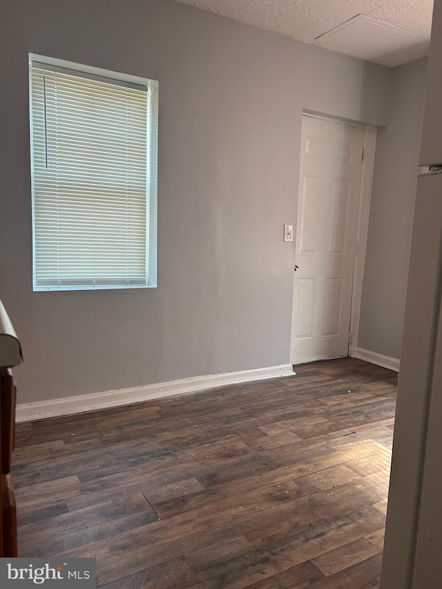 spare room featuring a textured ceiling and dark hardwood / wood-style flooring