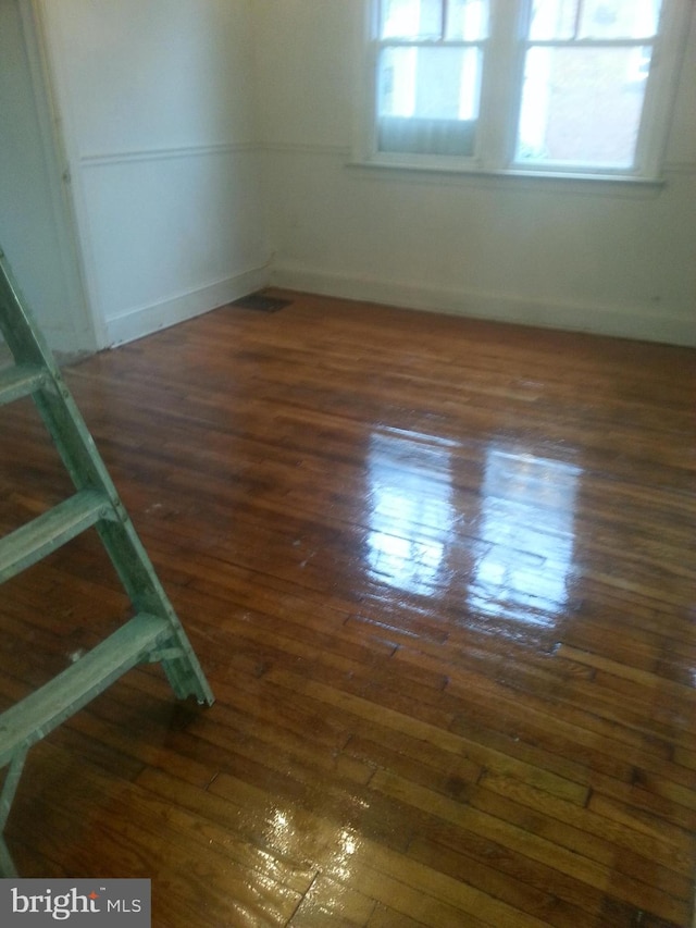 spare room featuring a healthy amount of sunlight and dark wood-type flooring