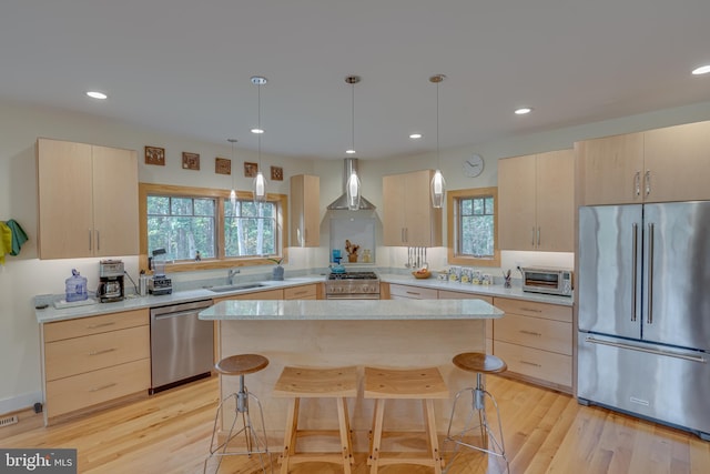 kitchen featuring a kitchen island, wall chimney range hood, light hardwood / wood-style flooring, stainless steel appliances, and light brown cabinetry