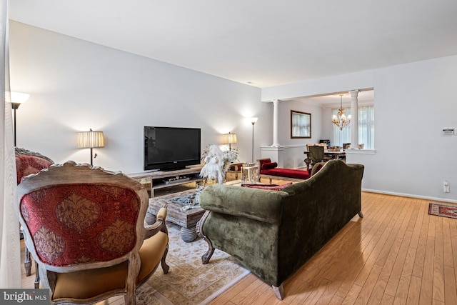 living room featuring light hardwood / wood-style flooring, a notable chandelier, and decorative columns