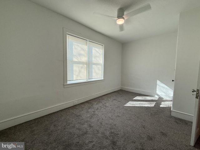 spare room featuring dark colored carpet and ceiling fan