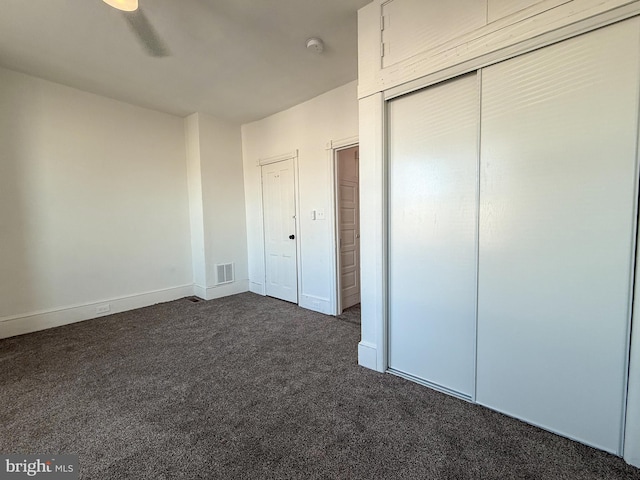 unfurnished bedroom with ceiling fan and dark carpet