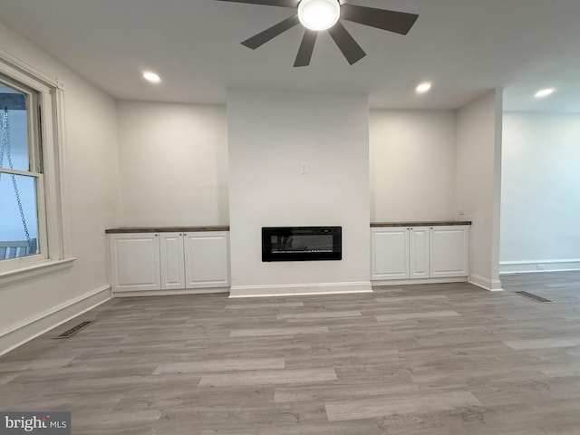 unfurnished living room featuring heating unit, ceiling fan, and light hardwood / wood-style flooring