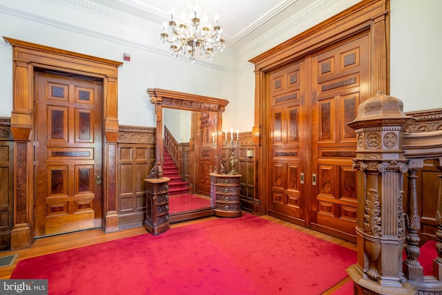 interior space featuring an inviting chandelier, ornamental molding, and hardwood / wood-style floors