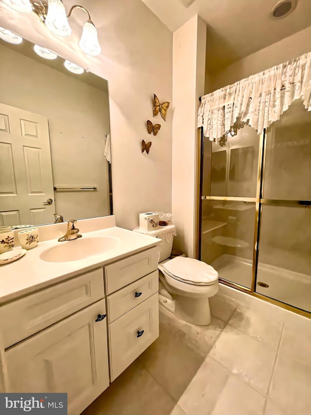 bathroom with vanity, a shower with shower door, toilet, and tile patterned floors