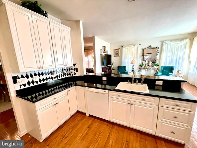 kitchen with dishwasher, kitchen peninsula, wood-type flooring, sink, and white cabinets