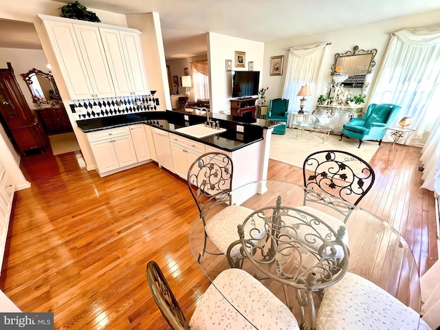 kitchen featuring kitchen peninsula, white cabinets, sink, and light wood-type flooring