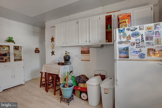 kitchen with white cabinets, white fridge, and light wood-type flooring