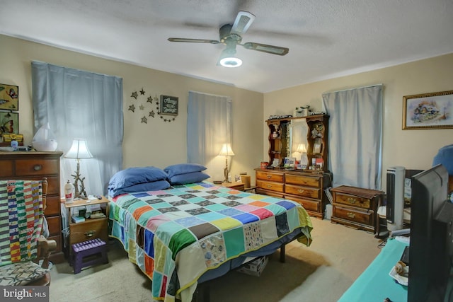 carpeted bedroom featuring ceiling fan and a textured ceiling