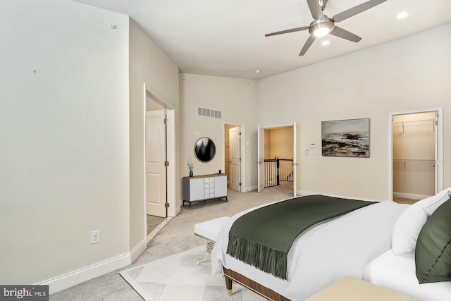 carpeted bedroom with a towering ceiling, a walk in closet, a closet, and ceiling fan