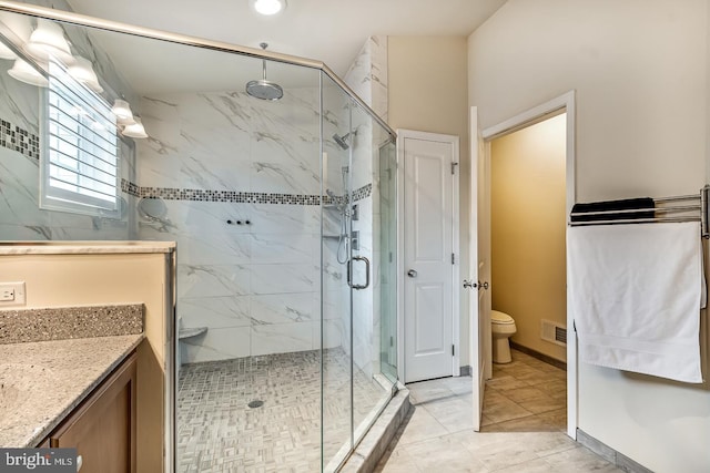 bathroom featuring vanity, a shower with shower door, and toilet