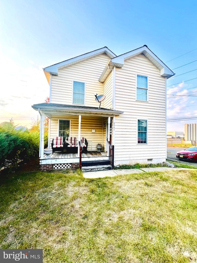 rear view of property featuring a lawn and covered porch