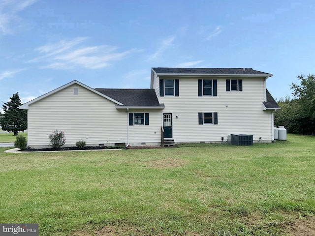 rear view of house featuring central air condition unit and a lawn