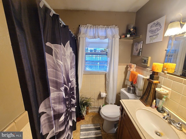 bathroom with vanity, toilet, tile patterned floors, and tile walls