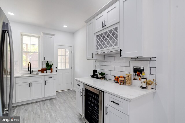 kitchen featuring white cabinets, wine cooler, sink, and stainless steel fridge