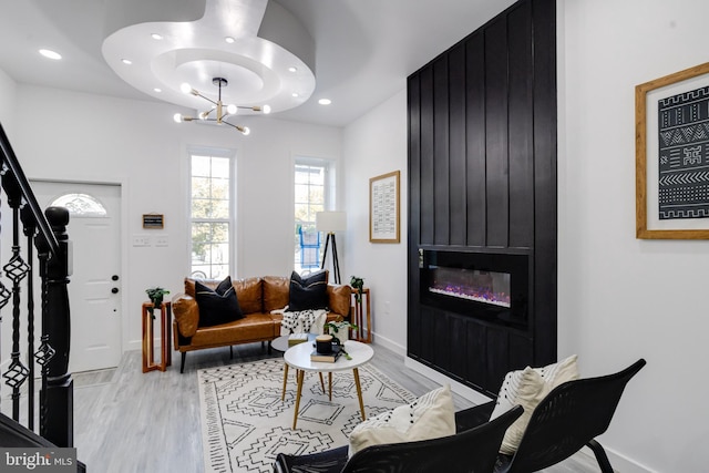 living room with a large fireplace, light hardwood / wood-style flooring, and a chandelier