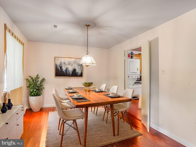 dining space with stacked washer / dryer and hardwood / wood-style flooring