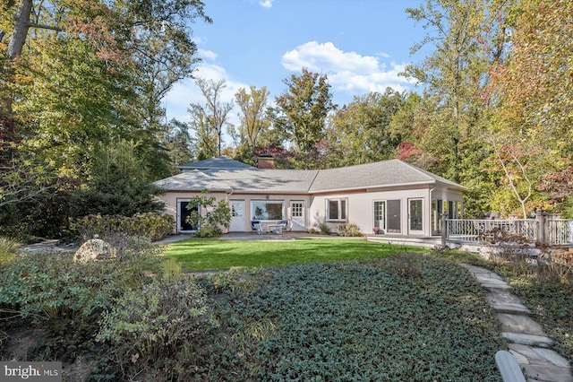 back of property with a lawn and a patio