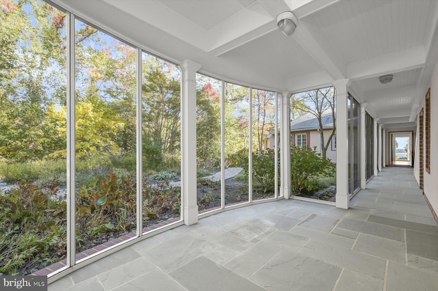 unfurnished sunroom featuring beamed ceiling