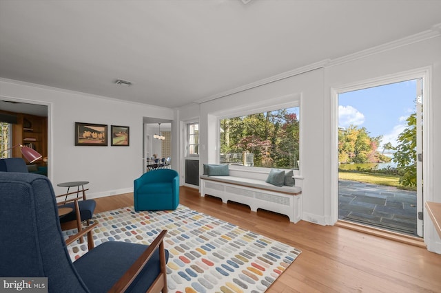 living room featuring wood-type flooring, an inviting chandelier, and crown molding