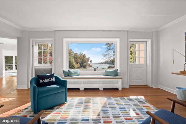 sitting room with hardwood / wood-style floors, crown molding, radiator, and a wealth of natural light