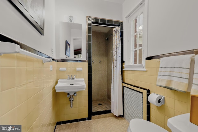 bathroom with toilet, sink, tile walls, and a shower with curtain