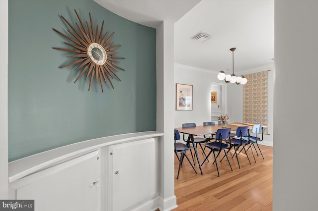 dining area with hardwood / wood-style floors, ornamental molding, and a chandelier