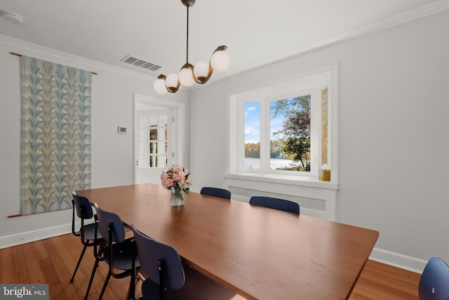 dining room with crown molding, wood-type flooring, and a chandelier