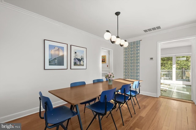 dining area with hardwood / wood-style floors, crown molding, and a chandelier