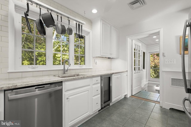 kitchen featuring sink, white cabinets, beverage cooler, stainless steel dishwasher, and light stone countertops