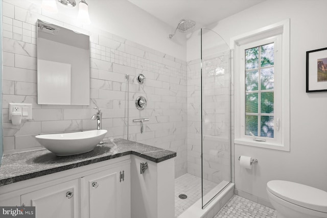 bathroom with vanity, tiled shower, tile patterned floors, and toilet