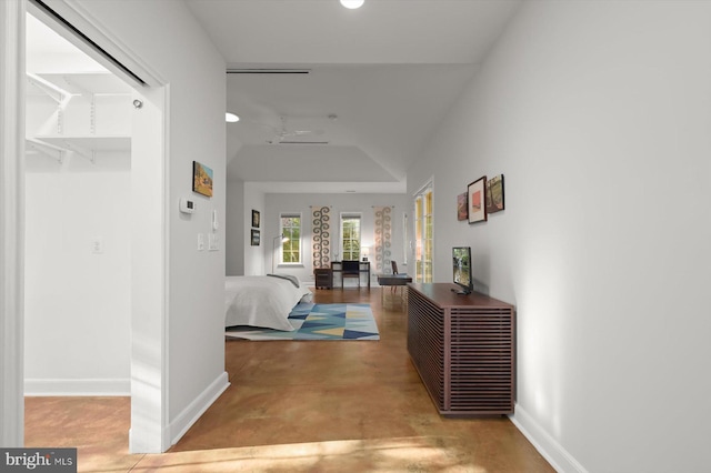 corridor with concrete flooring and lofted ceiling