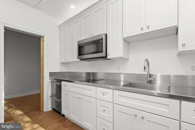 kitchen with white cabinetry, sink, and stainless steel counters