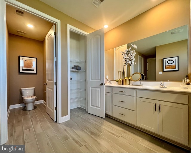 bathroom with toilet, hardwood / wood-style flooring, and vanity