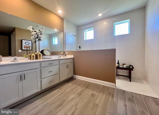 bathroom featuring vanity, wood-type flooring, and tiled shower