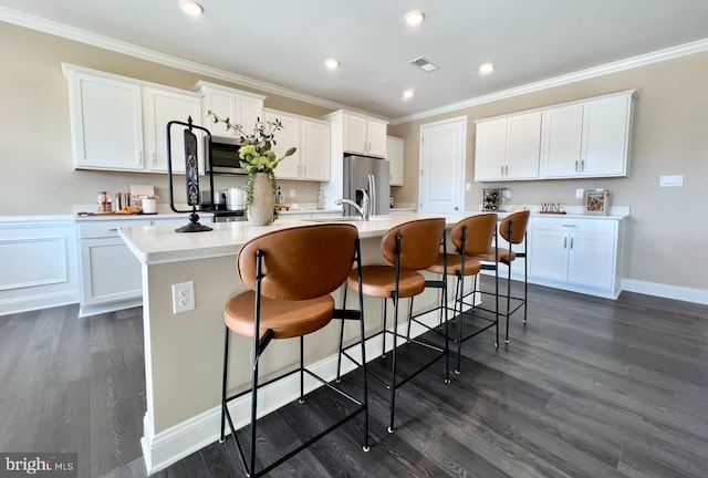 kitchen featuring dark hardwood / wood-style flooring, white cabinetry, stainless steel appliances, and an island with sink