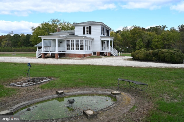 rear view of house featuring a yard and a sunroom