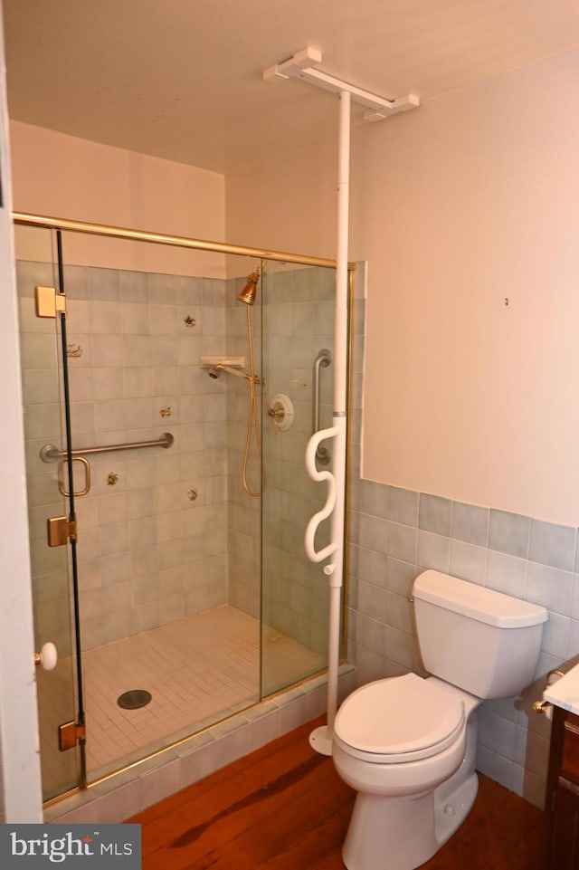 bathroom featuring toilet, wood-type flooring, vanity, tile walls, and an enclosed shower