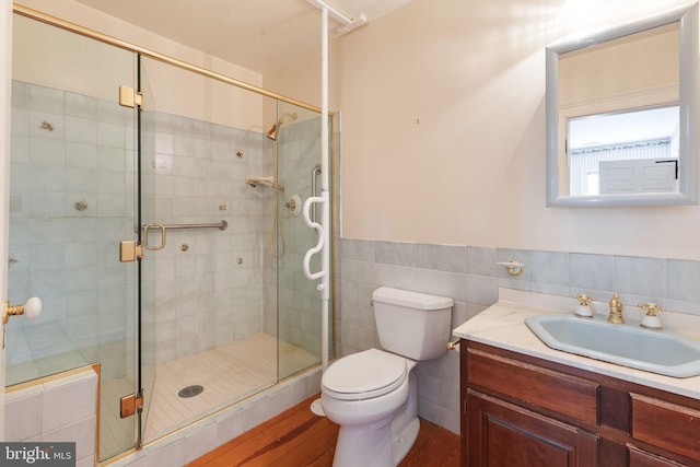 bathroom featuring a shower with door, vanity, hardwood / wood-style floors, and toilet