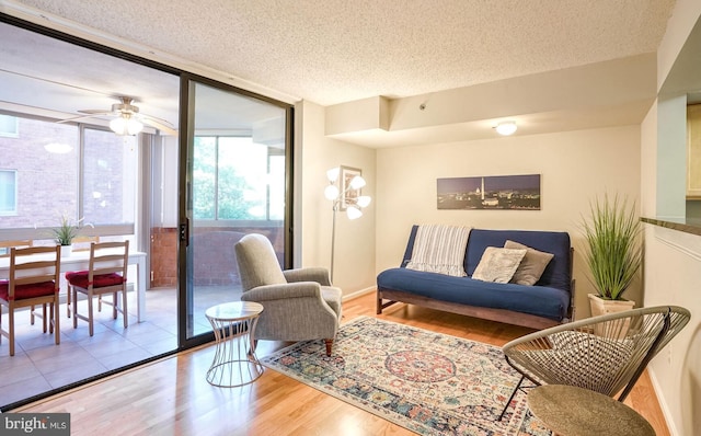 living room featuring light hardwood / wood-style floors, a textured ceiling, expansive windows, and ceiling fan