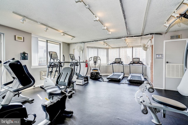 workout area featuring rail lighting and a textured ceiling