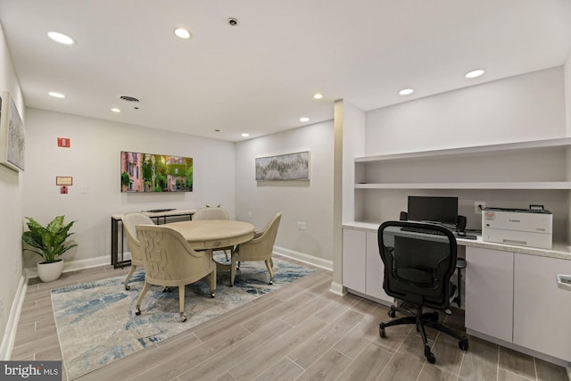 dining area with built in desk and light hardwood / wood-style floors