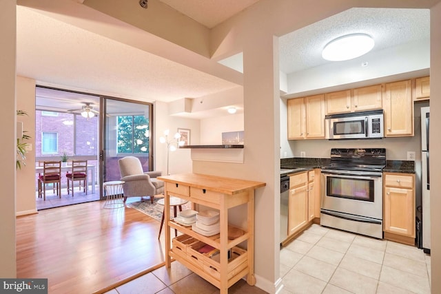 kitchen featuring light brown cabinets, light hardwood / wood-style flooring, appliances with stainless steel finishes, a textured ceiling, and ceiling fan