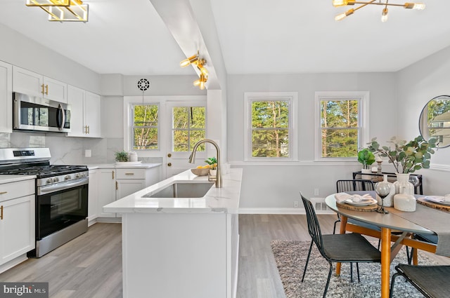 kitchen with light hardwood / wood-style floors, white cabinetry, stainless steel appliances, and sink