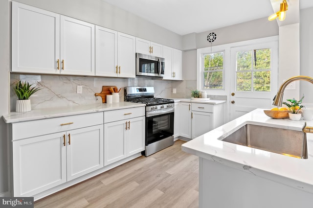 kitchen featuring appliances with stainless steel finishes, light hardwood / wood-style flooring, white cabinetry, and sink